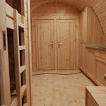 Interior dining space with twin bedroom doors and curved timber walls in the Hearthwood Pod glamping pod