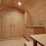Interior dining space with twin bedroom doors and curved timber walls in the Hearthwood Pod glamping pod