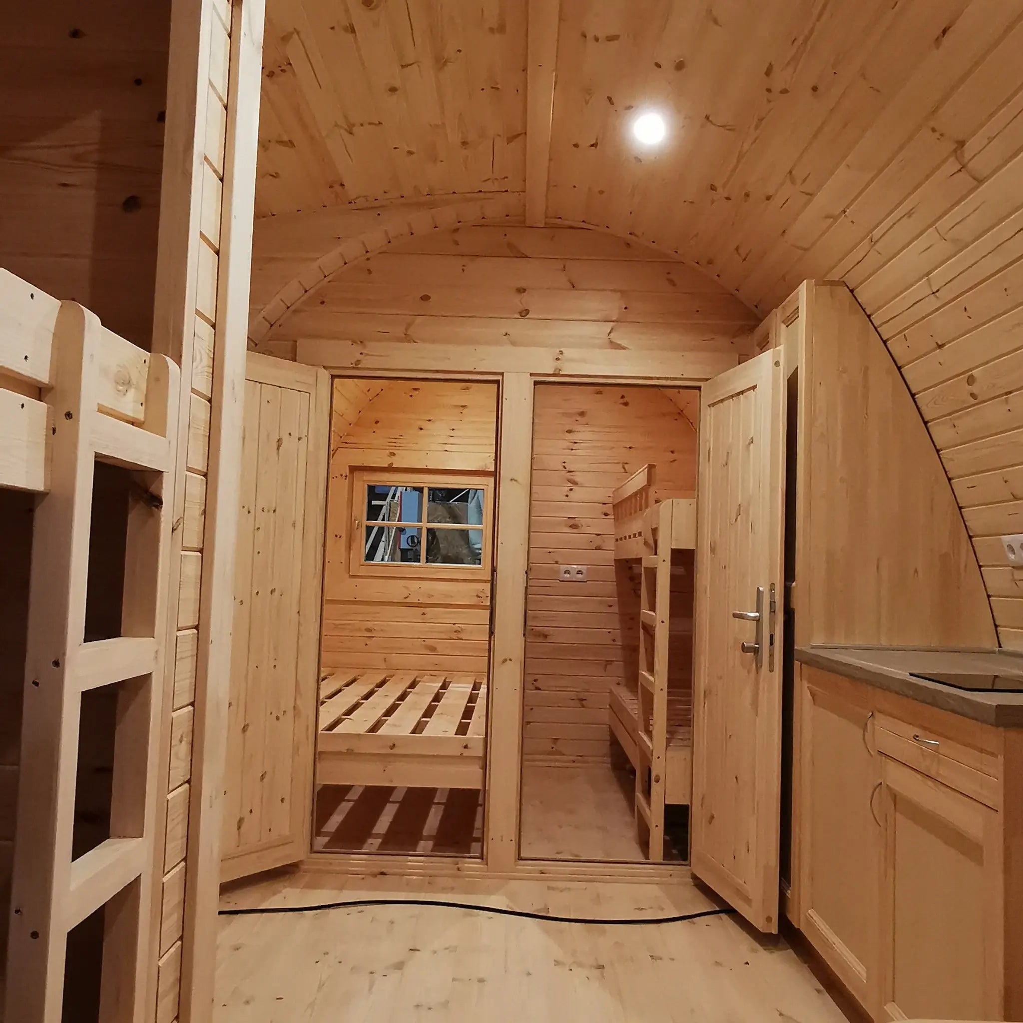 Interior view of twin bedroom doors and edge of kitchenette counter inside the Hearthwood luxury 6 person glamping pod