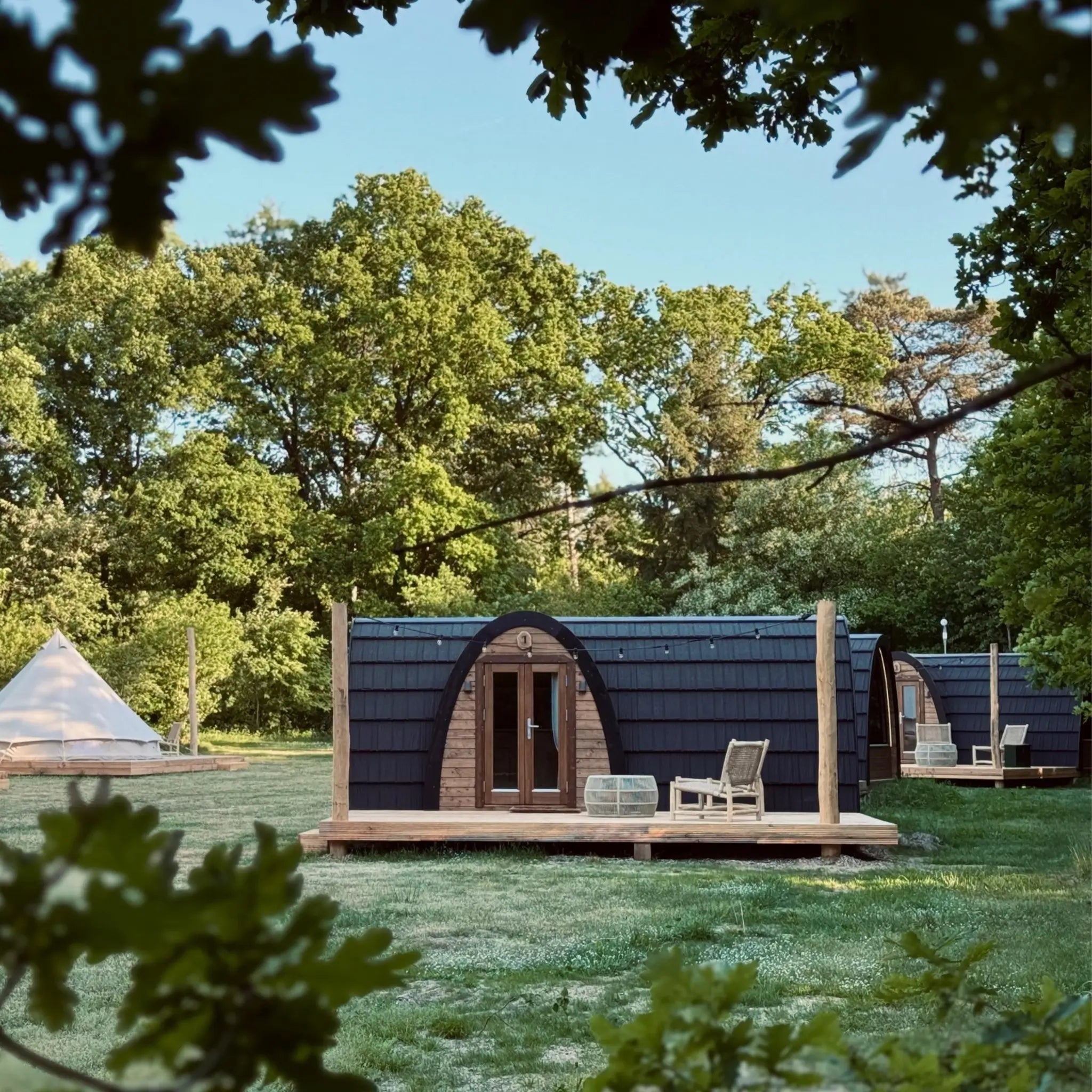 Front view of The Hobbit Pod luxury glamping pod on a timber deck in a woodland setting