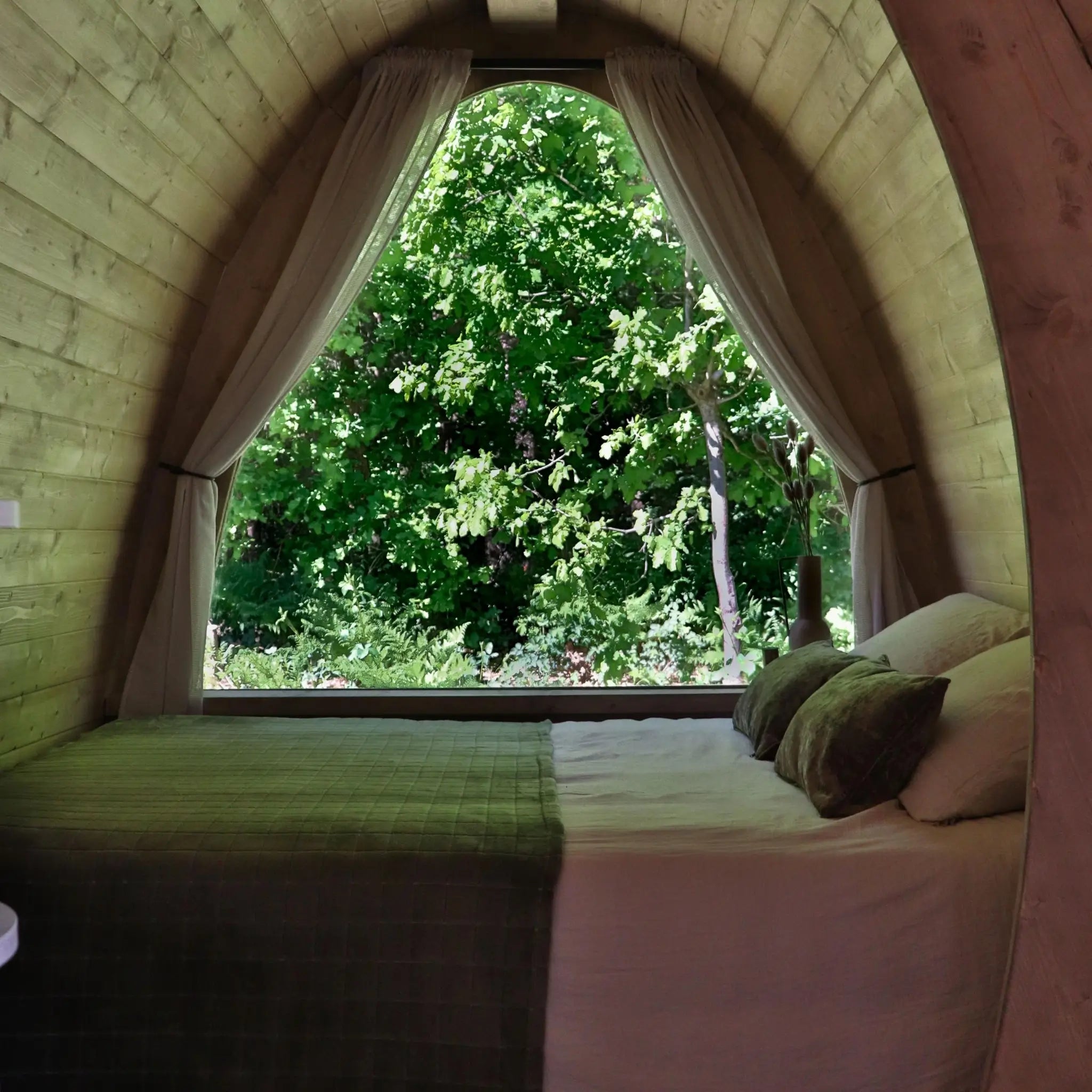 Sleeping area with panoramic full-height window inside The Hobbit Pod luxury glamping pod