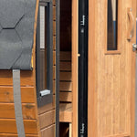 Open entrance door revealing the changing room inside the Infinity Glass barrel sauna