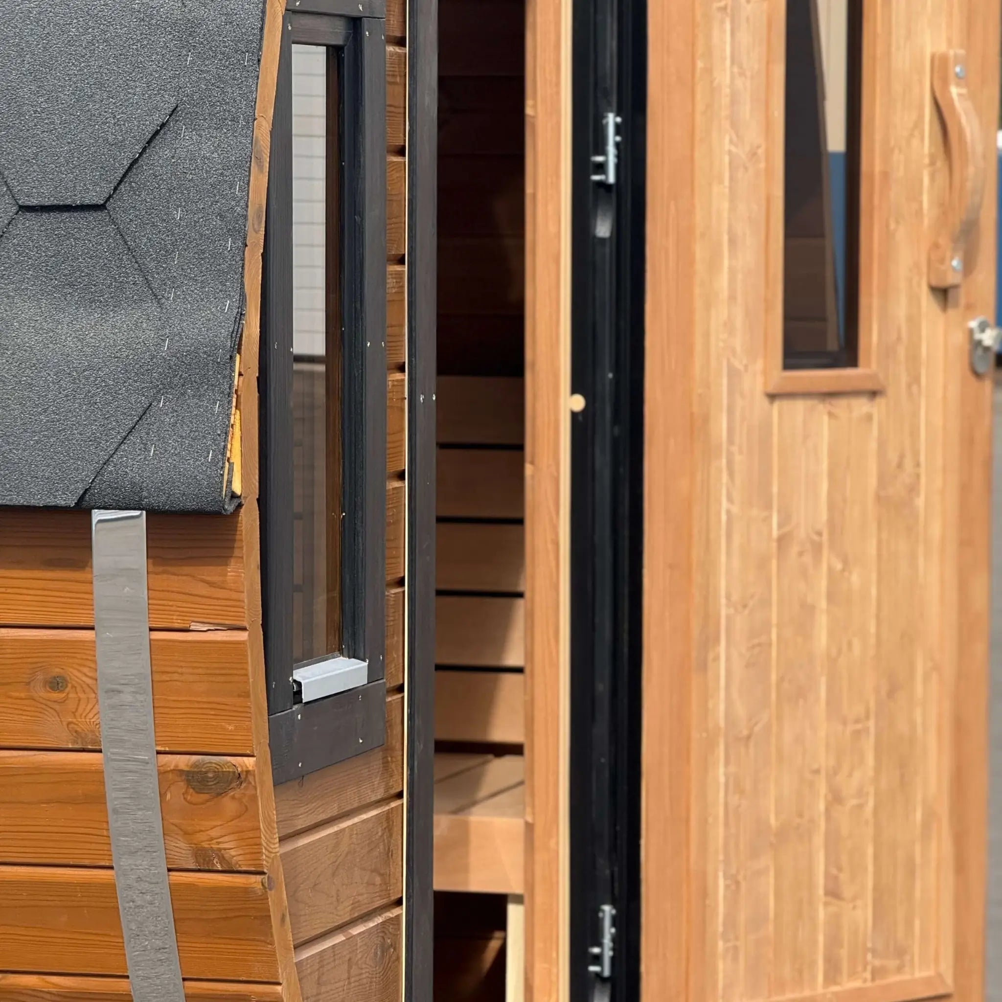 Open entrance door revealing the changing room inside the Infinity Glass barrel sauna