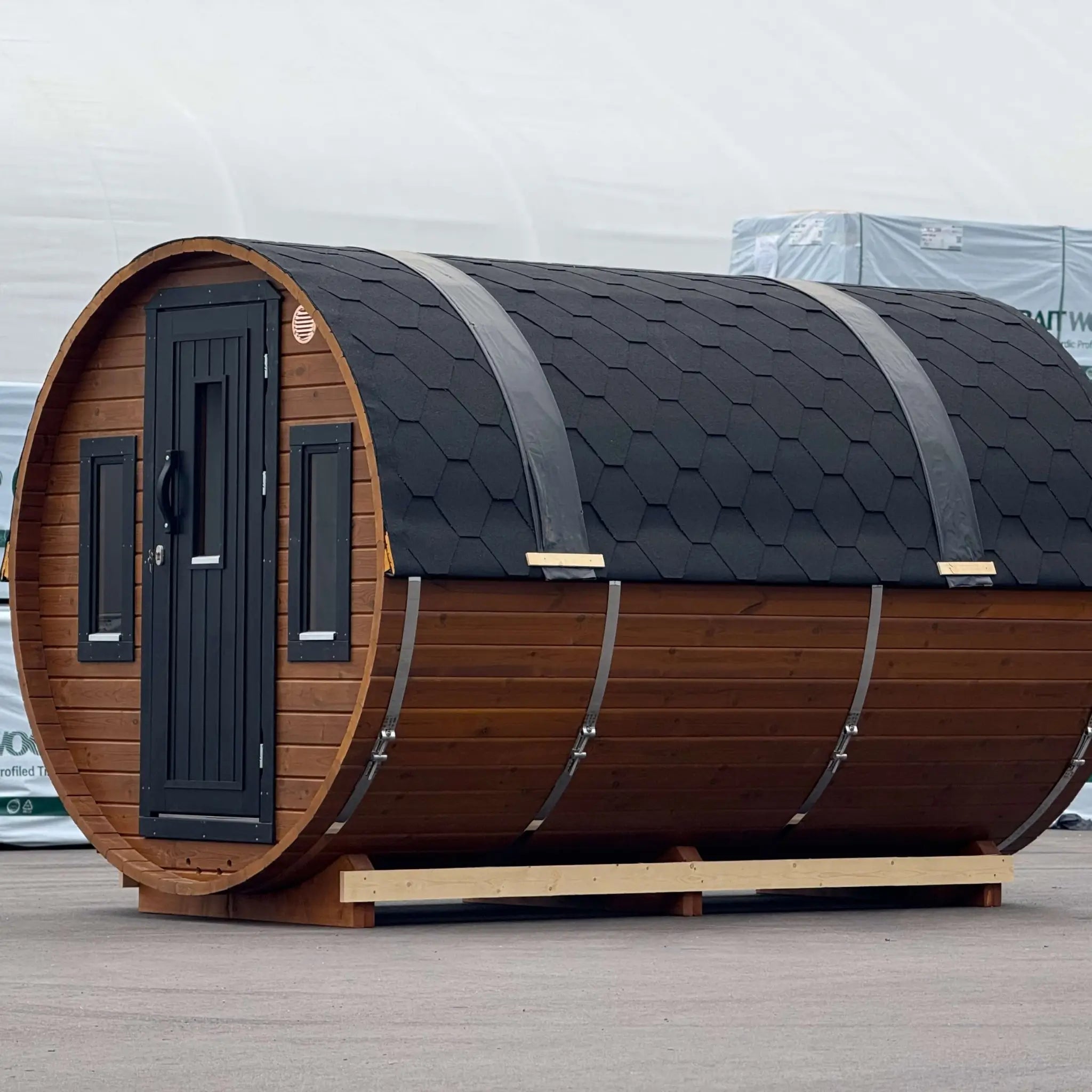 Side view of the Infinity Glass luxury 8 person barrel sauna with changing room