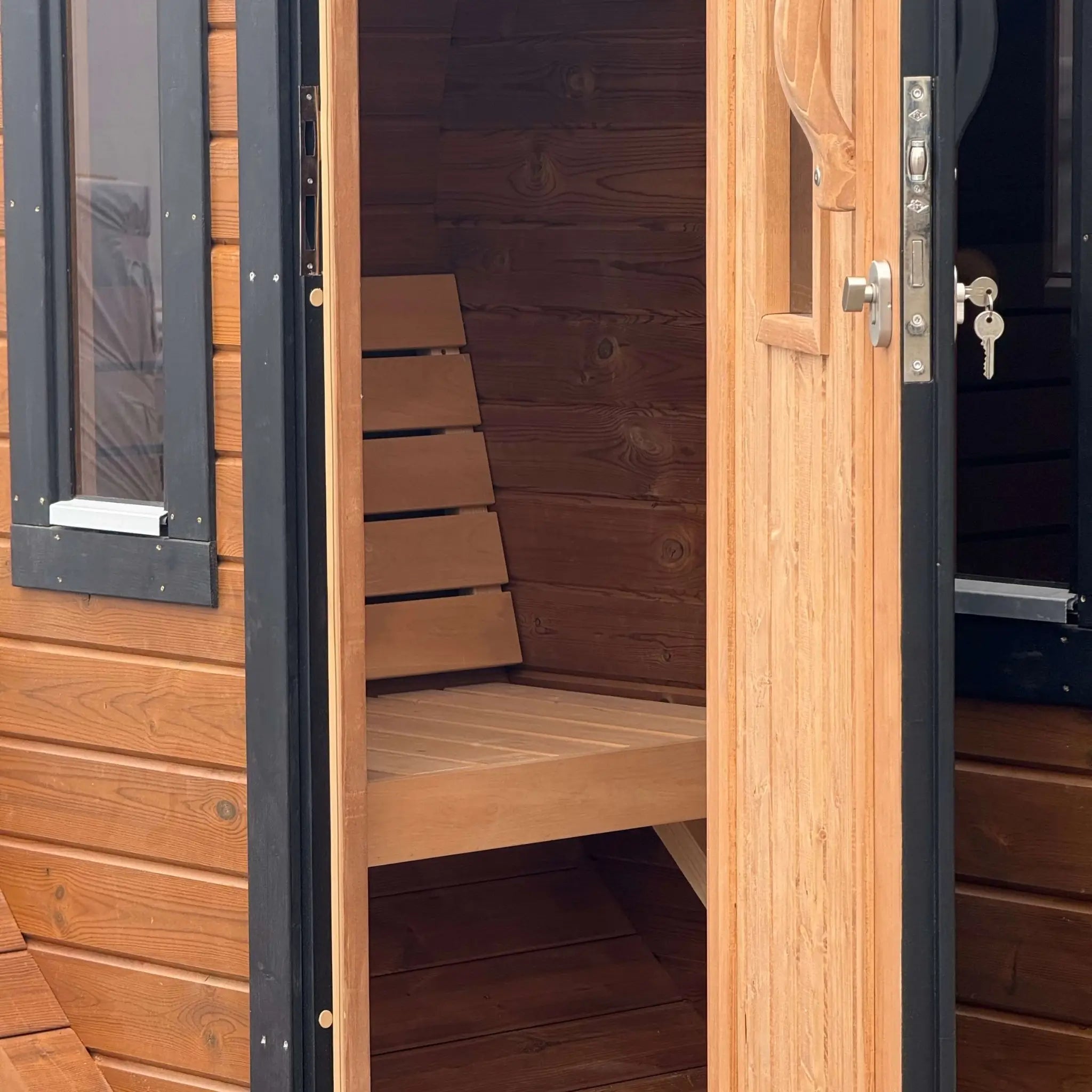 Changing room viewed through the open entrance door of the Infinity Glass luxury barrel sauna