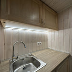 The Large GlampTainer container-style glamping unit – close-up of stainless steel sink with chrome tap set into timber countertop and LED lighting