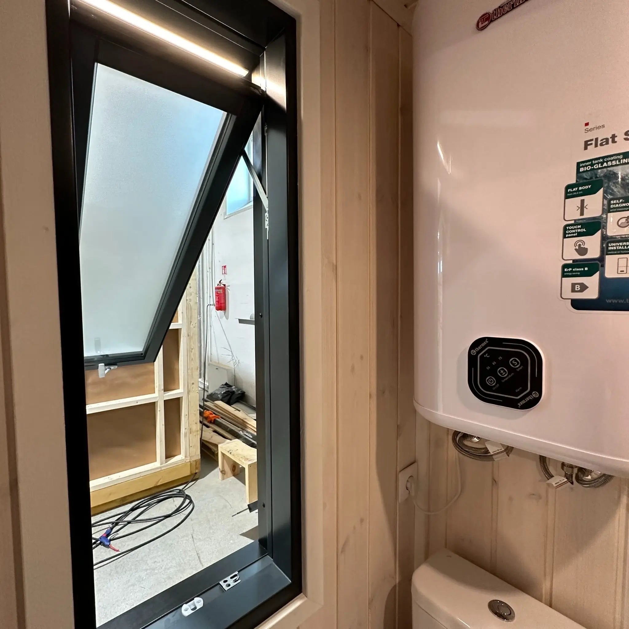 The Large GlampTainer container-style glamping unit – compact bathroom with toilet and wall-mounted water heater by open side window