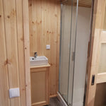 The Medium GlampTainer container-style glamping structure – modern bathroom with enclosed shower, square basin and wood-clad walls