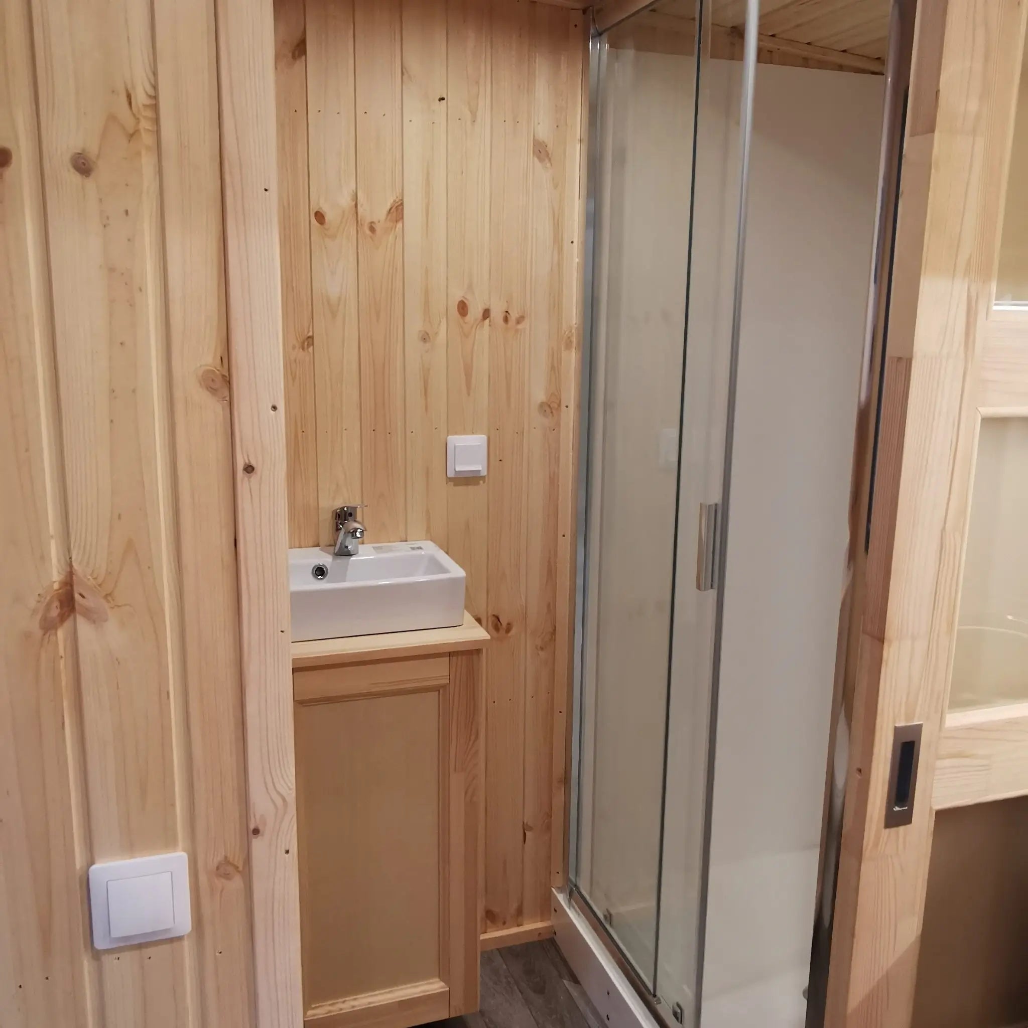 The Medium GlampTainer container-style glamping structure – modern bathroom with enclosed shower, square basin and wood-clad walls