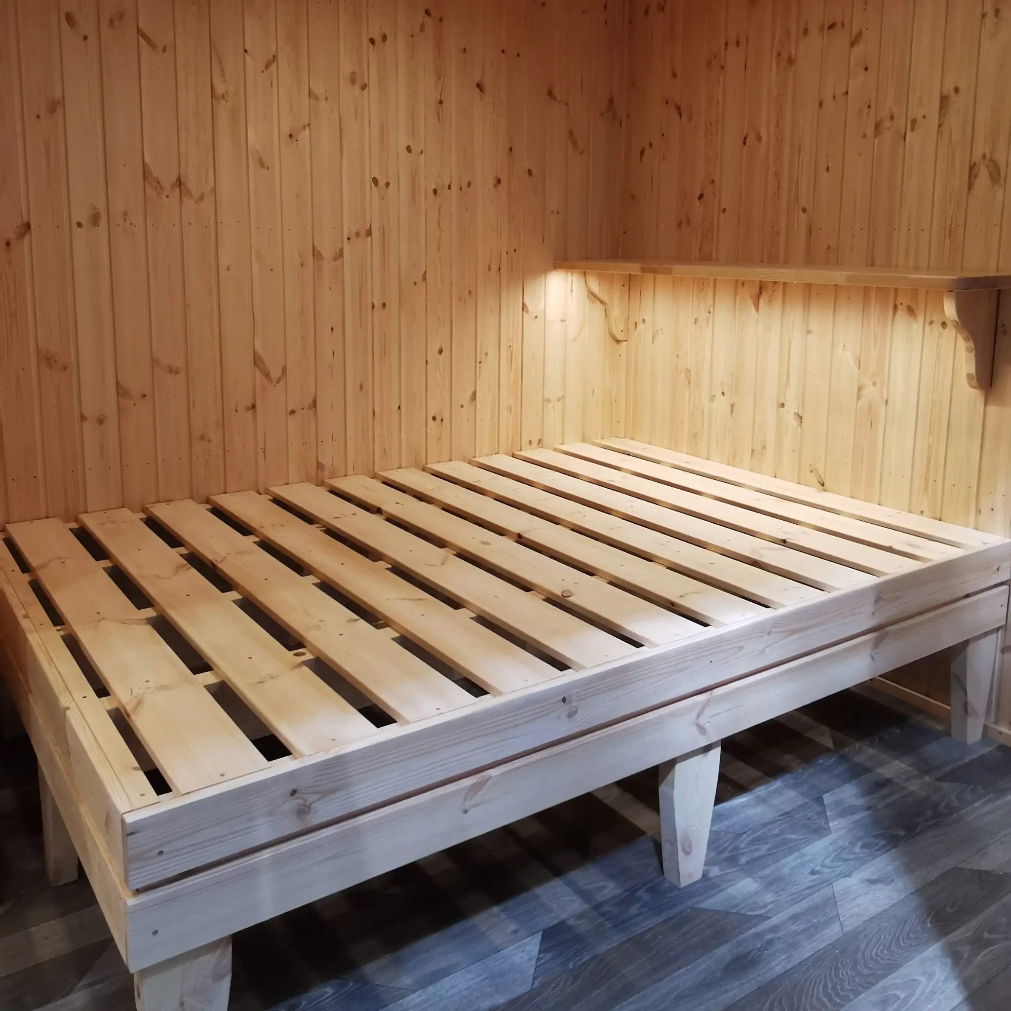 The Medium GlampTainer container-style glamping structure – side view of compact bed platform with overhead shelf in wood-clad glamping pod