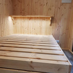 The Medium GlampTainer container-style glamping structure – space-saving bedroom with raised bed frame and slim timber shelf on the feature wall