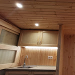 The Medium GlampTainer container-style glamping structure – compact kitchenette with overhead cabinets, under-cabinet LED lighting and timber ceiling panels