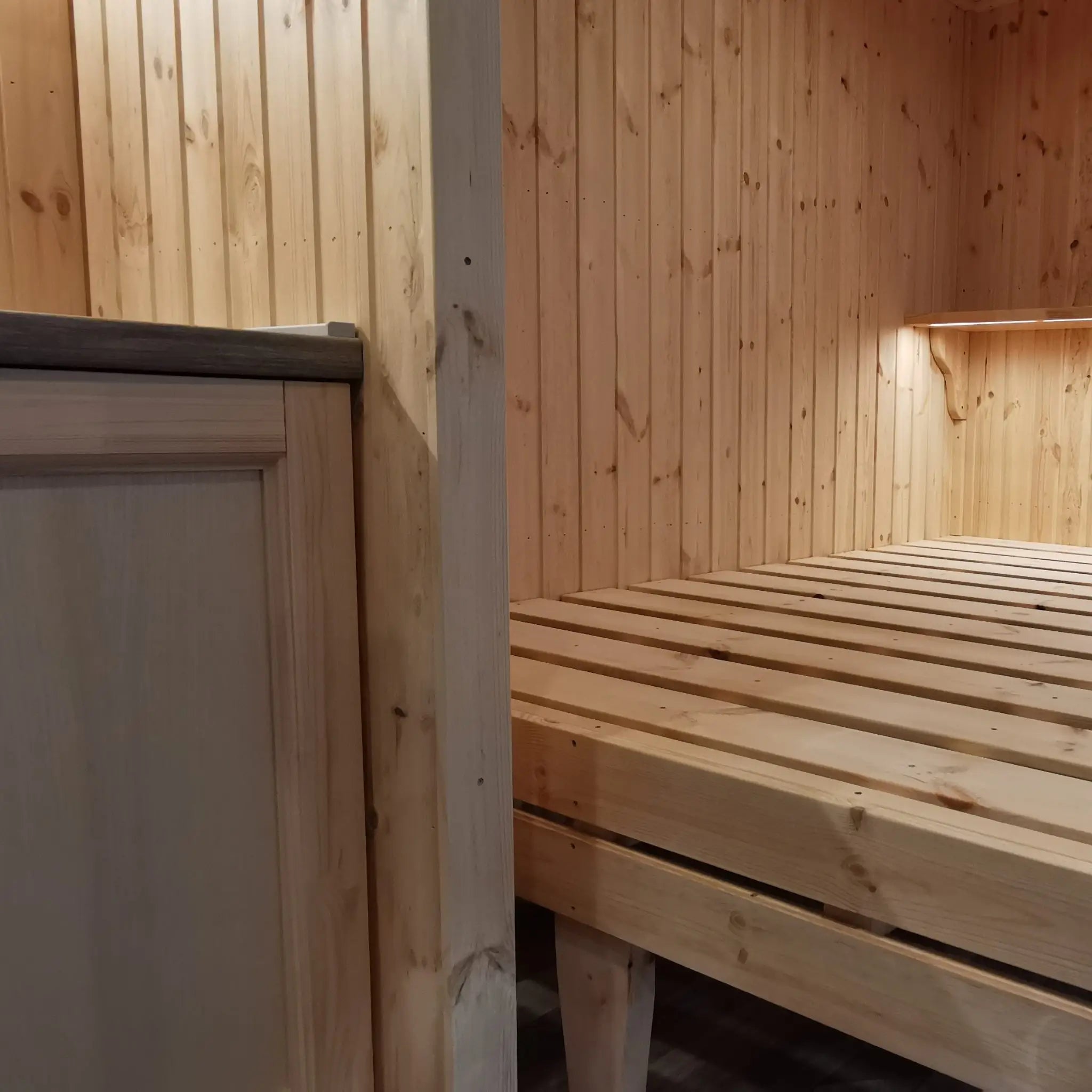 The Medium GlampTainer container-style glamping structure – wooden bed frame next to kitchenette with warm pine cladding