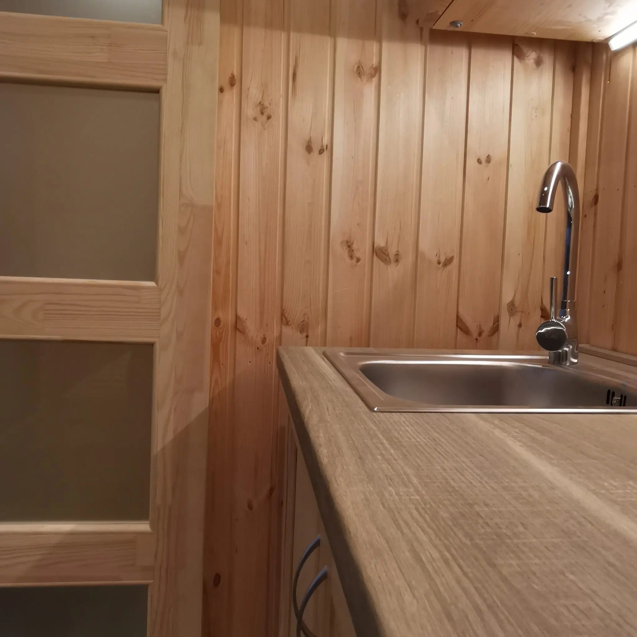 The Medium GlampTainer container-style glamping structure – modern stainless steel sink with curved tap set against vertical timber cladding