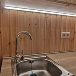 The Medium GlampTainer container-style glamping structure – stainless steel sink under soft LED strip lighting on pine wall panels