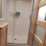 The Medium GlampTainer container-style glamping structure – walk-in shower with glass panels and compact vanity sink near sliding door