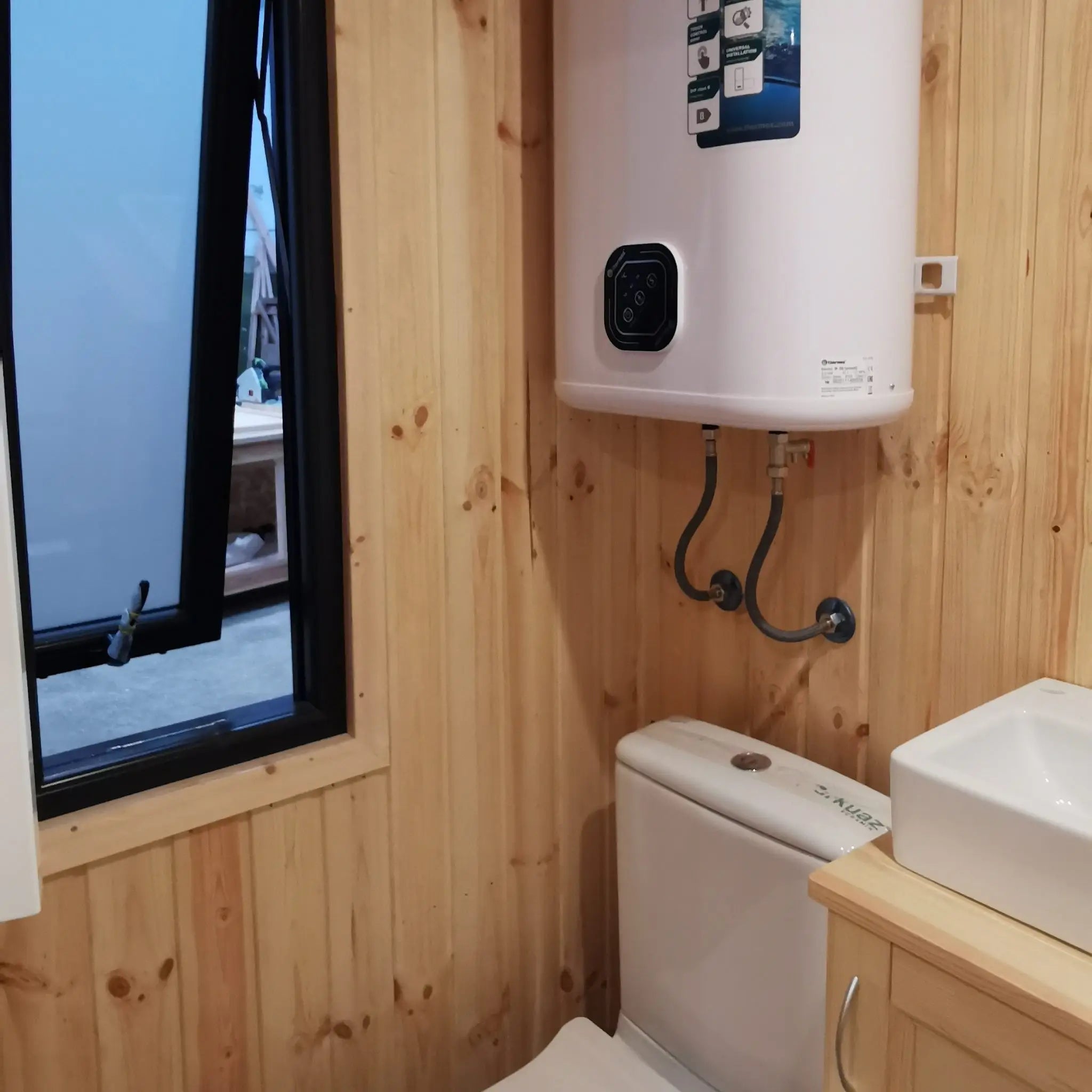 The Medium GlampTainer container-style glamping structure – bathroom corner with toilet and water heater beside open frosted window