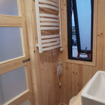 The Medium GlampTainer container-style glamping structure – slim bathroom window with wall-mounted heated towel rail and sliding door entrance