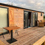 Luxury shepherd’s hut with spacious timber decking, outdoor seating and open double doors