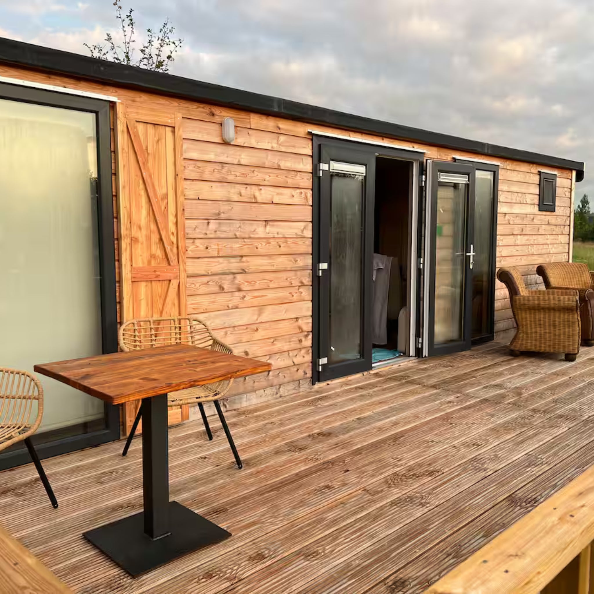 Luxury shepherd’s hut with spacious timber decking, outdoor seating and open double doors