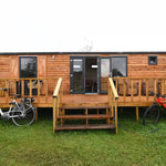 Full front view of luxury shepherd’s hut with raised timber decking and countryside setting