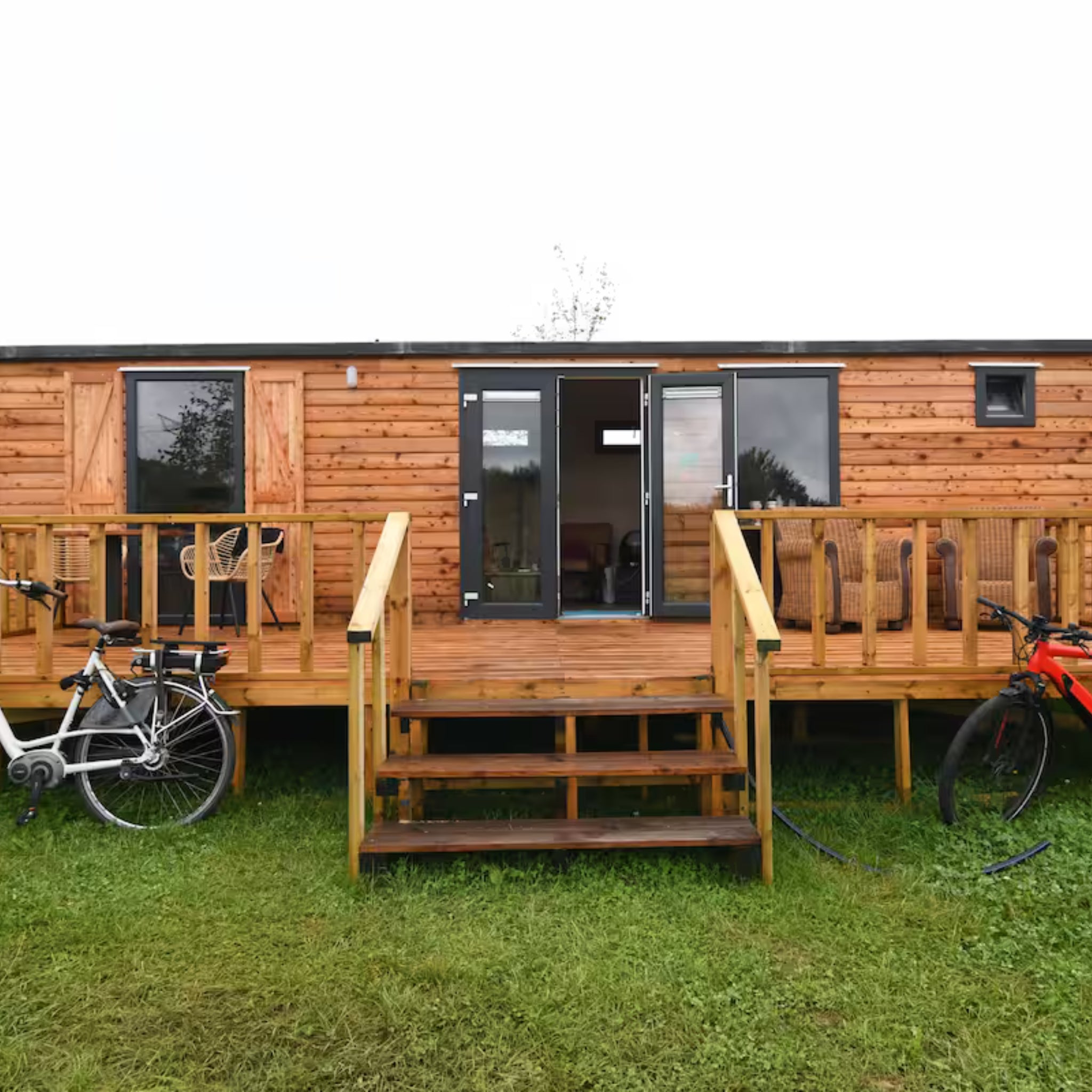 Full front view of luxury shepherd’s hut with raised timber decking and countryside setting