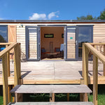 Front entrance of luxury shepherd’s hut with large decking and modern glass doors