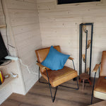 Comfortable living area inside shepherd’s hut with leather chairs and stylish wooden décor