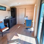 Open-plan interior of luxury shepherd’s hut featuring living area and kitchenette