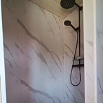 Contemporary shower room inside luxury shepherd’s hut with marble-effect walls and black fittings