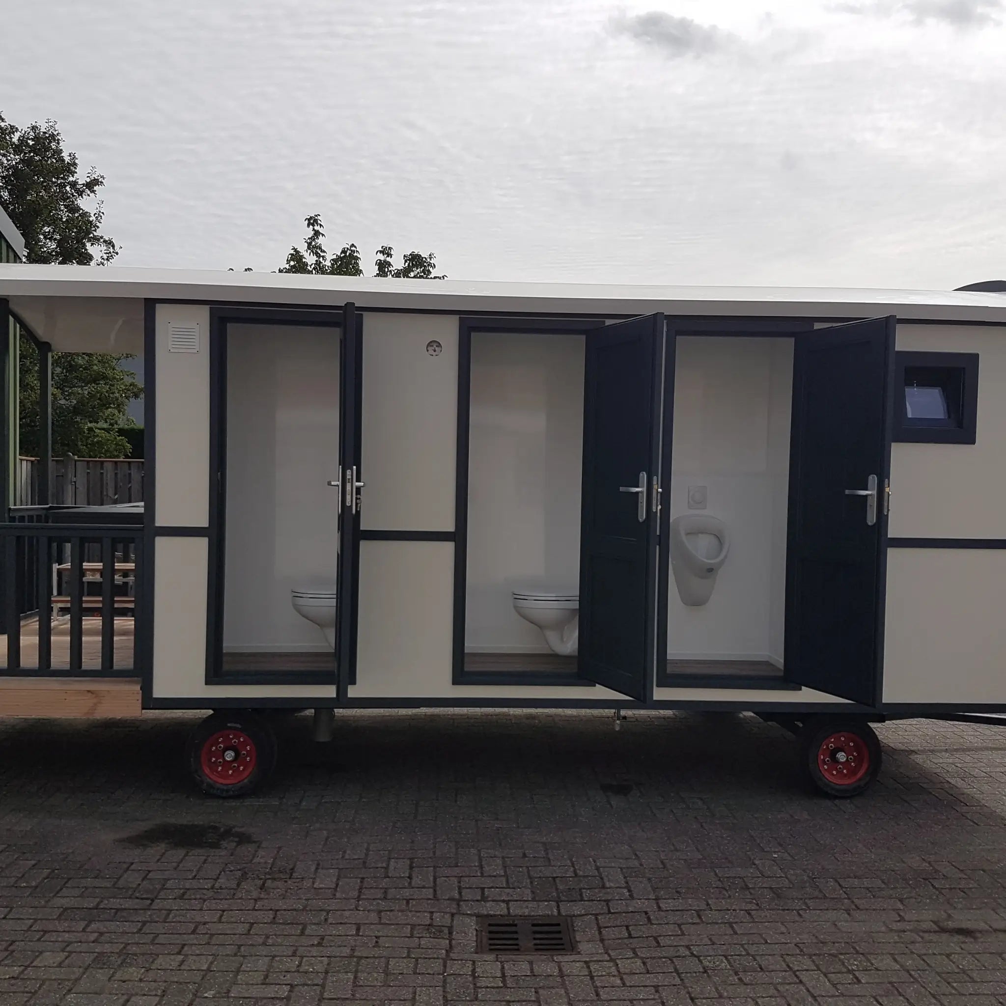 Side view of washroom hut with opened toilet doors and modern black exterior