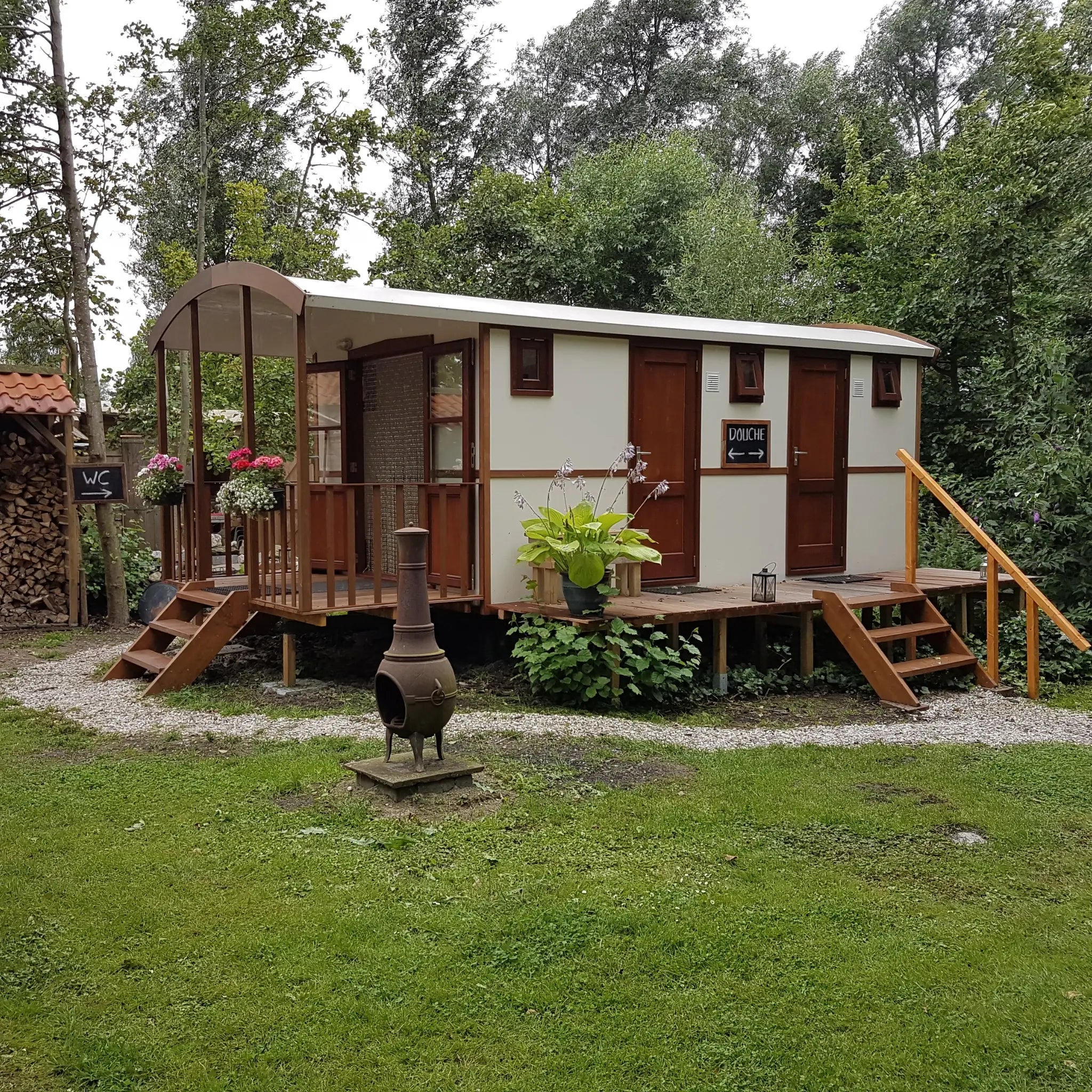 Side view of washroom hut with outdoor decking, pathway and woodland backdrop