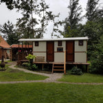 Side exterior view of luxury washroom hut with raised timber decking and landscaped garden