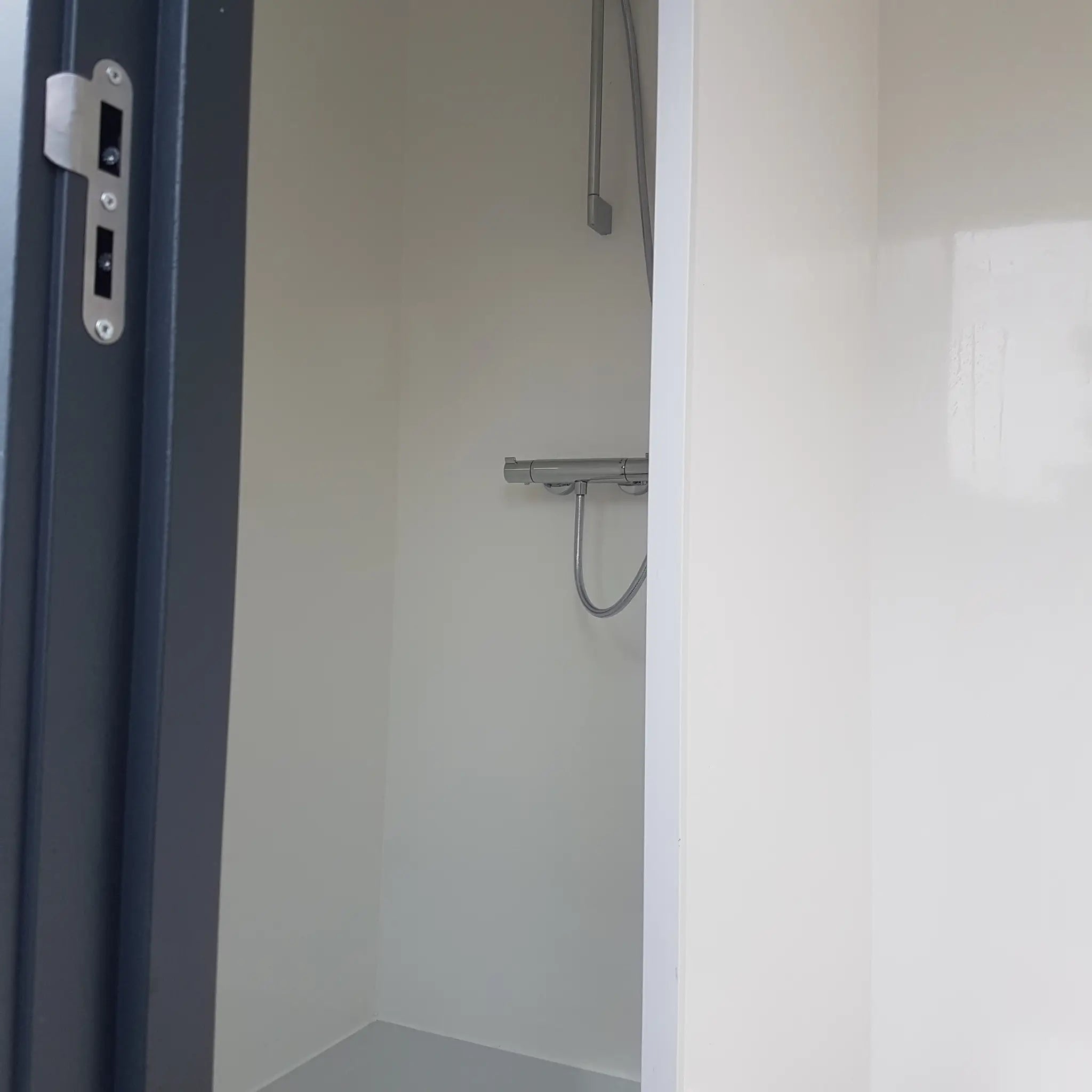 Compact shower area with mounted mixer shower inside luxury washroom hut