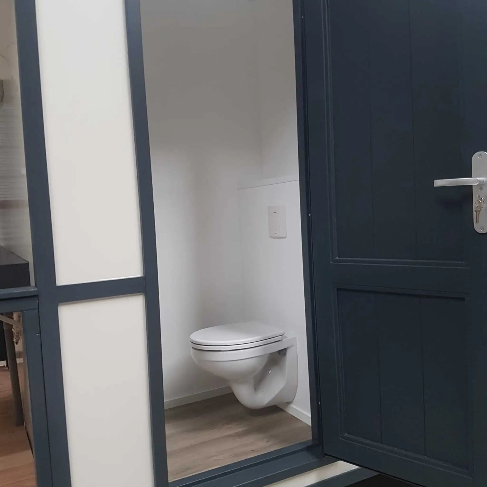 Modern toilet cubicle interior with wall-mounted toilet inside shepherds hut washroom