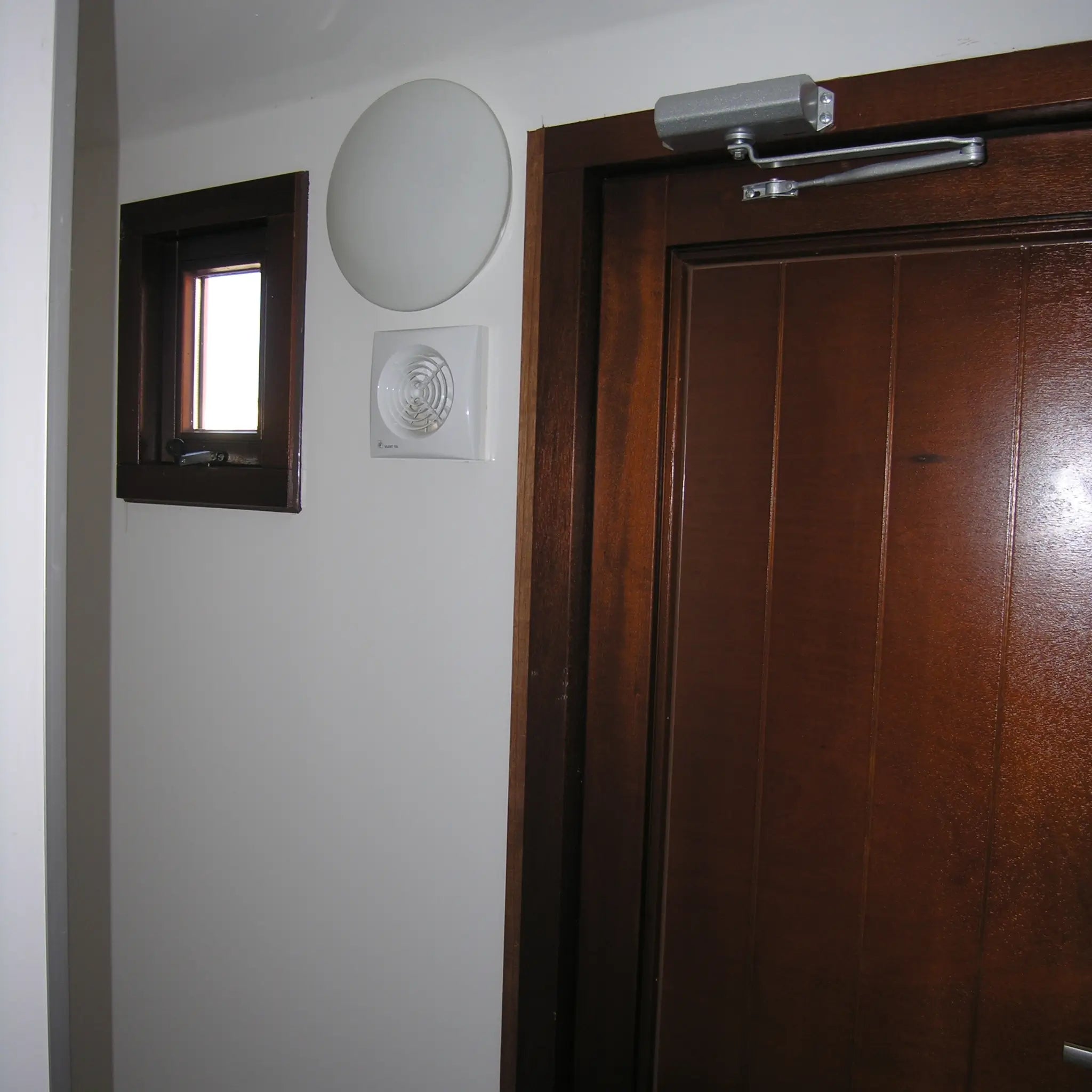 Interior ventilation fan and wooden washroom cubicle door inside shepherds hut bathroom unit
