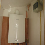 Compact Bosch water heater and utility connections installed inside shepherds hut technical room