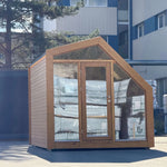 Front exterior view of luxury timber glamping pod with panoramic glass frontage, modern cabin design and full-height entrance door.