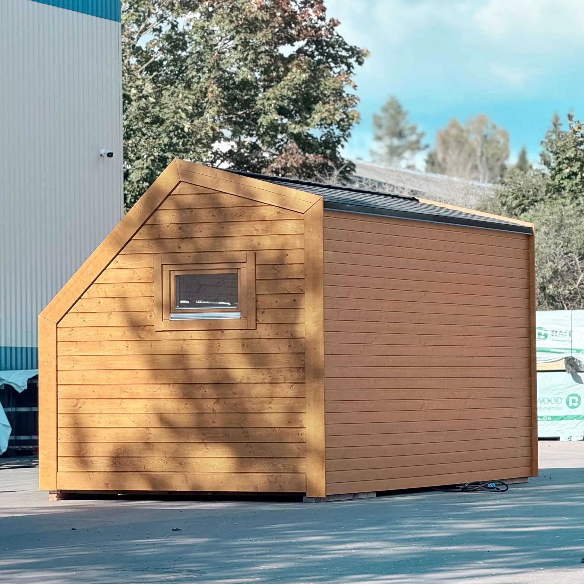Rear exterior view of compact wooden glamping pod with modern cladding, minimalist architecture and private window feature.