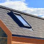 Close-up of insulated skylight roof window on luxury glamping pod with modern shingle roofing and timber exterior finish.