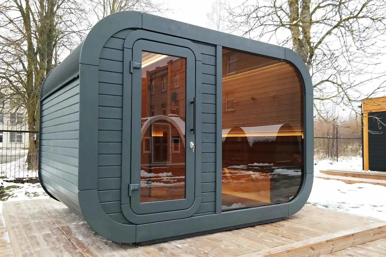 Wooden outdoor sauna next to glamping pods in a UK countryside setting.