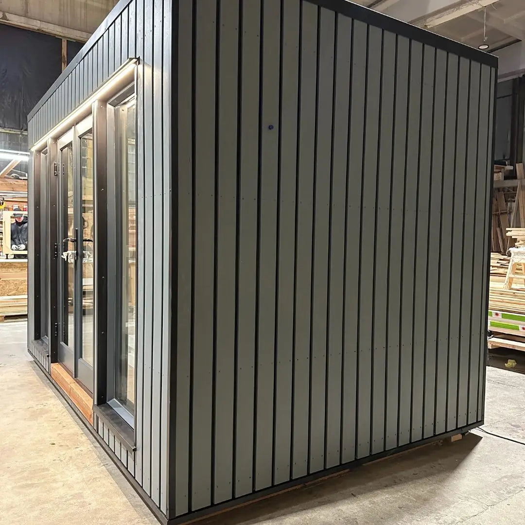 The Small GlampTainer container-style glamping structure – clean side view showing dark-grey vertical cladding and modern minimalist exterior.