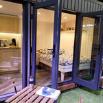 Fully furnished Small GlampTainer container-style glamping structure – cosy sleeping area with double bed, kitchenette and outdoor bistro setup on artificial grass.