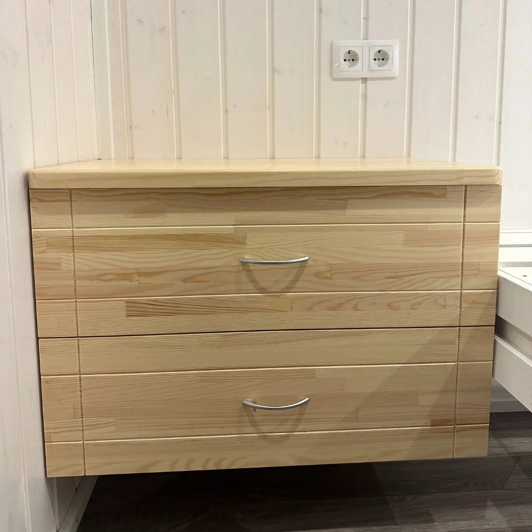 Close-up of sleek wooden nightstand inside The Small GlampTainer container-style glamping structure – two drawers with modern handles and light timber finish.