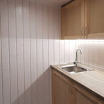Close-up of kitchenette area in The Small GlampTainer container-style glamping structure – stainless steel sink, light wood cabinets and LED strip lighting.
