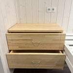 Floating wooden nightstand inside The Small GlampTainer container-style glamping structure – two smooth-sliding drawers offering compact storage beside bed frame.