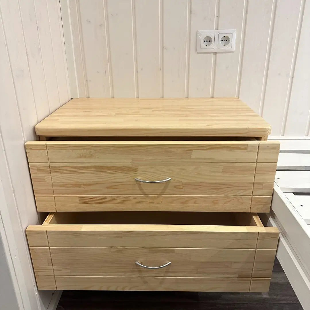 Floating wooden nightstand inside The Small GlampTainer container-style glamping structure – two smooth-sliding drawers offering compact storage beside bed frame.