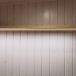Soft-lit shelf above bed frame inside The Small GlampTainer container-style glamping structure – integrated LED strip creating warm ambient bedroom lighting.