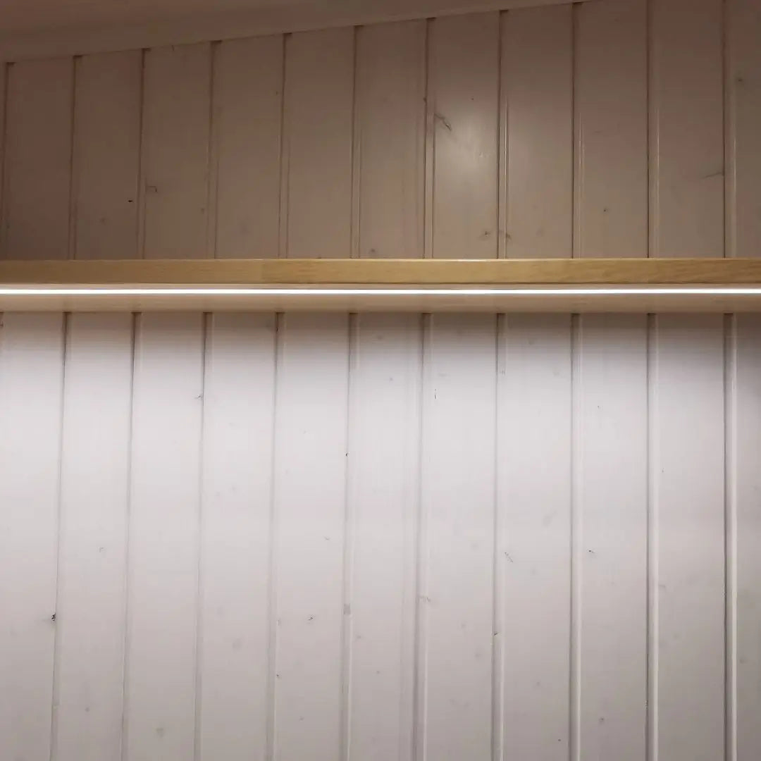 Soft-lit shelf above bed frame inside The Small GlampTainer container-style glamping structure – integrated LED strip creating warm ambient bedroom lighting.