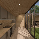 Modern fitted kitchen with timber interior, courtyard glazing and bathroom access inside the ultimate 2 person glamping pod during daylight.